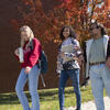 three students walking together on a fall day.